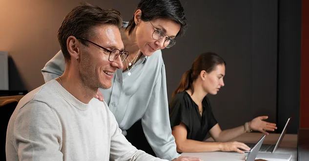 Trois collaborateurs d’un office travaillant ensemble devant des ordinateurs portables