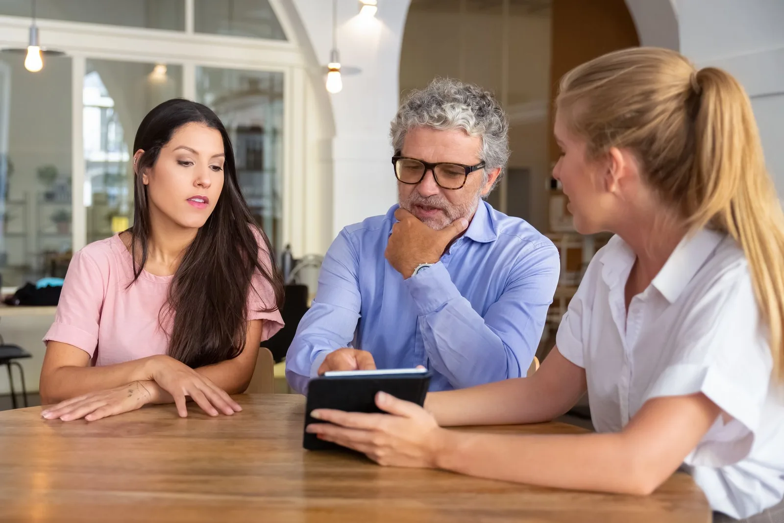 Une conseillère présente la solution sur une tablette à deux clients autour d’une table